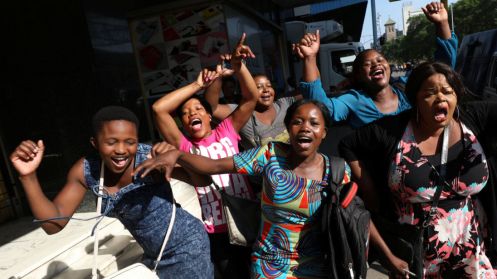 Zimbabweans celebrate in the morning sun after President Mugabe resigned in Harare