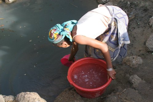 Sa'a Ali collects water from a dirty pond